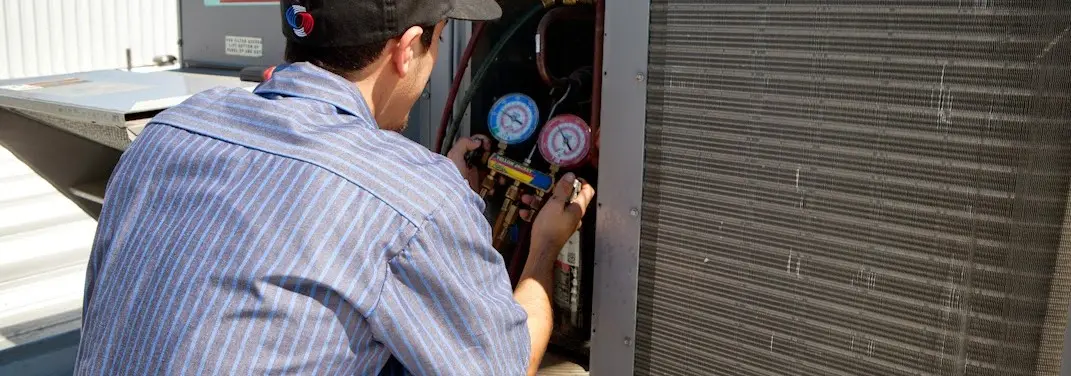 HVAC technician servicing a condenser unit in Harris