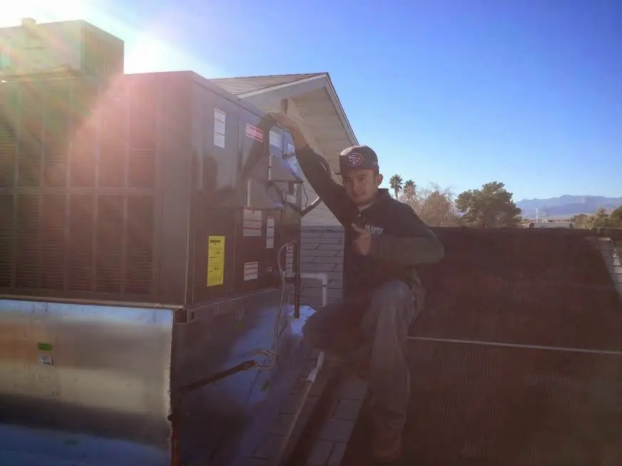 HVAC technician performing Air Duct Repair on a rooftop unit in Harris